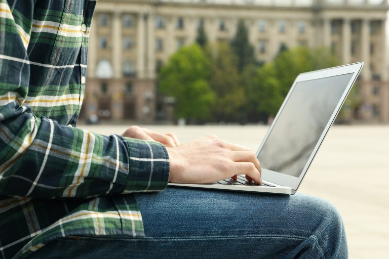 Man with laptop works outdoor. Free work schedule